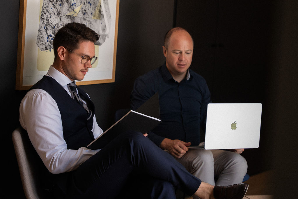 Troi team members reviewing project data and timelines on a laptop and in a notebook during a focused planning session in a modern office environment